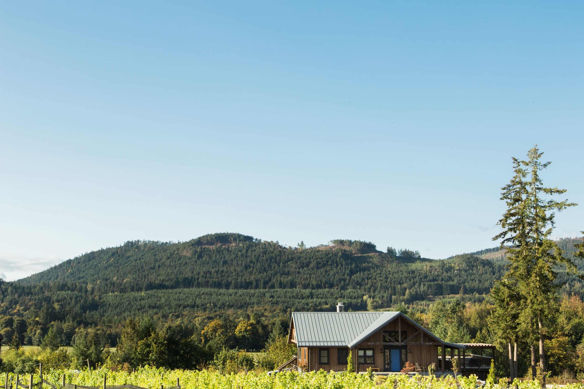 A home with sloping mountains in the background on a Cowichan Valley winery on Vancouver Island, BC.