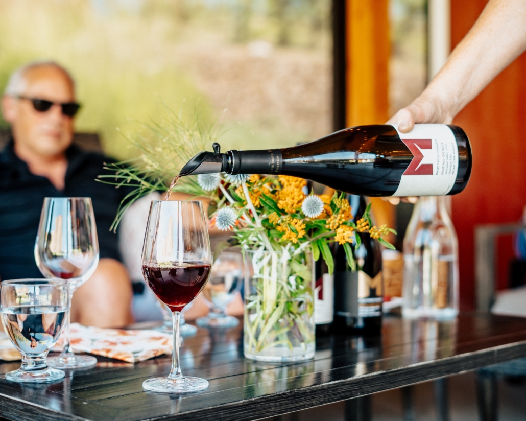 A bottle of Meyer Family Vineyards wine being poured into a wine glass on a sunny patio.