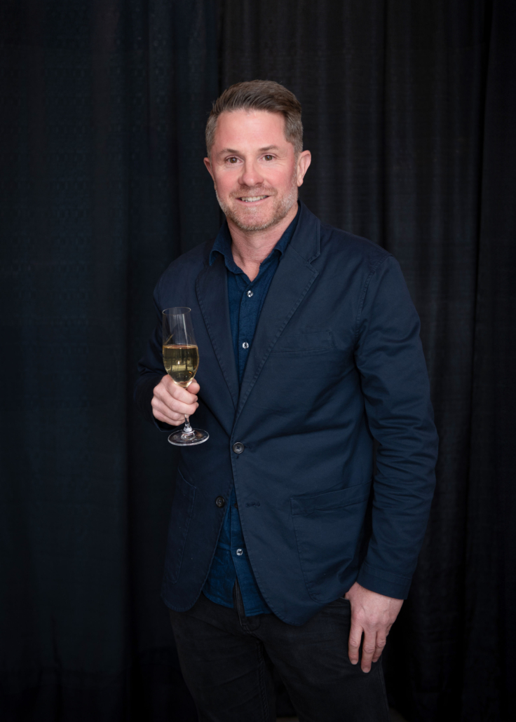 Rhys Pender of Little Farm Winery holding a glass of sparkling.